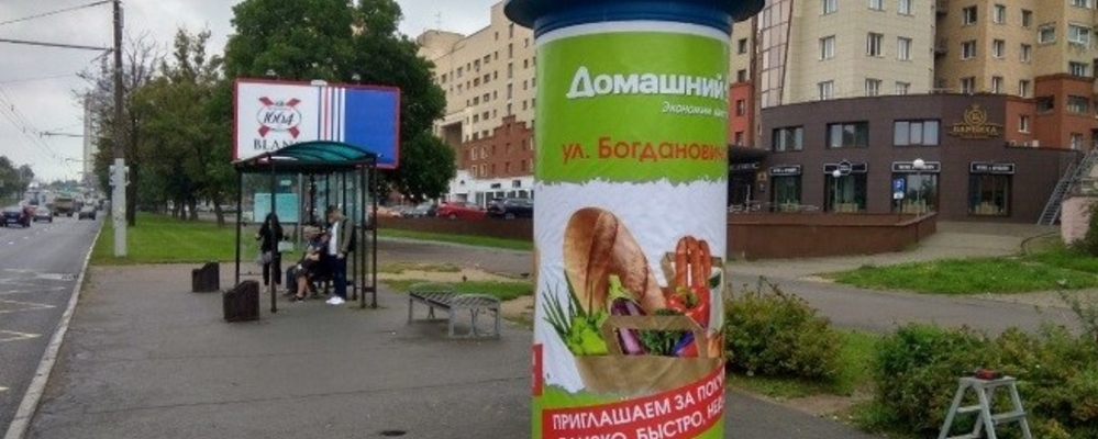Рекламная тумба в центре города с ярким постером бренда